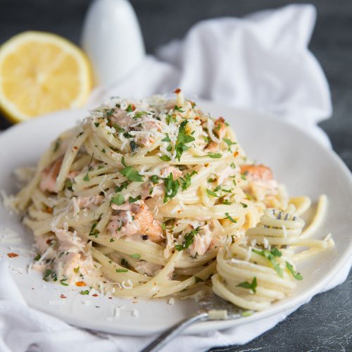 Salmon Pasta garnished with chilli flakes and parmesan