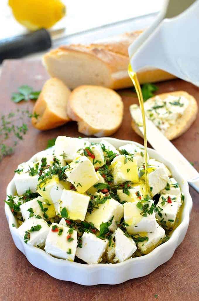 Olive oil being poured over Feta Marinated with Herbs and Chilli