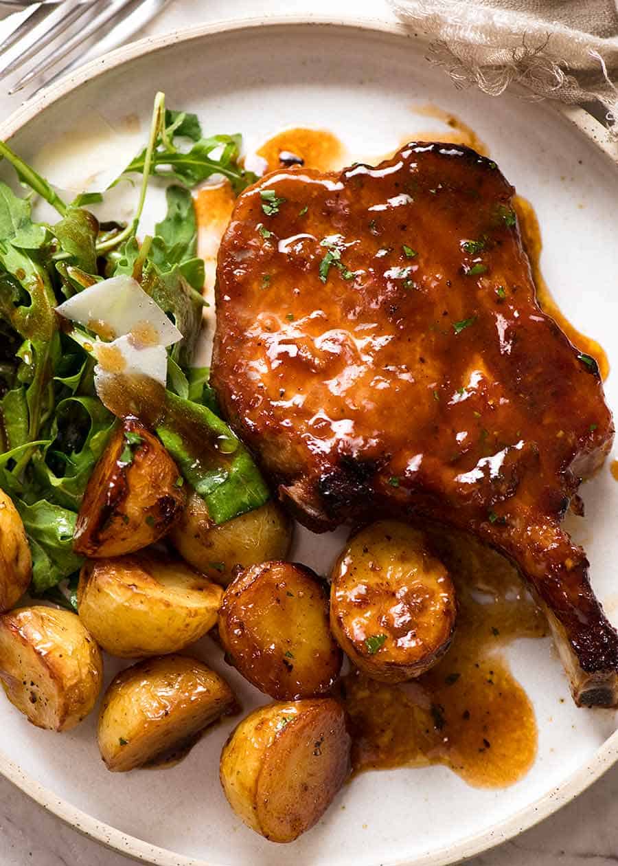 Overhead photo of Oven Baked Pork Chops with potatoes, with a side of Rocket with Parmesan and Balsamic