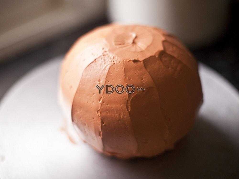 круглый корж, смазанный маслянным кремом оранжевого цвета